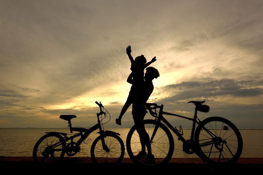 La silueta de dos personas junto a sus bicicletas en en la playa al atardecer.