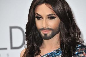 Plano medio de Conchita Wurst. Viste un vestido con lentejuelas y lleva el cabello suelto y barba.