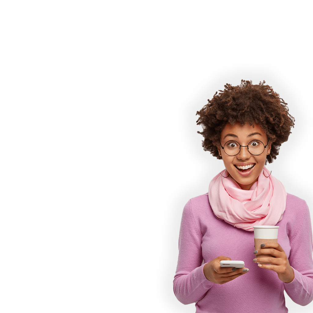 Imagen de una mujer mirando sonriente a la cámara. Sostiene en su mano derecha un dispositivo móvil y en la izquierda un café.