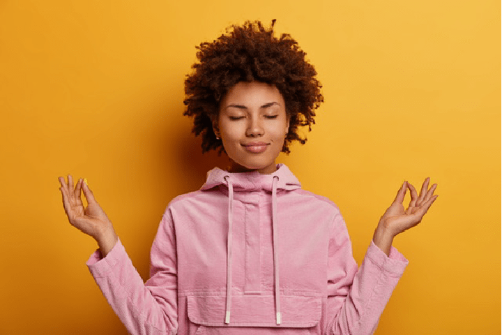 persona afrodescendiente con los ojos cerrados y los brazos en posición de yoga