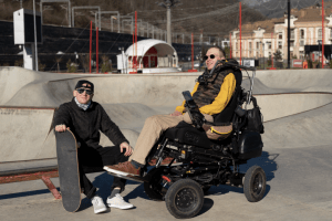 Dos hombres en un parque. Uno de los hombres está en una silla de ruedas.